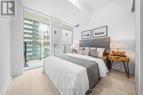 A bedroom with a large bed and a view of a city street through the window.