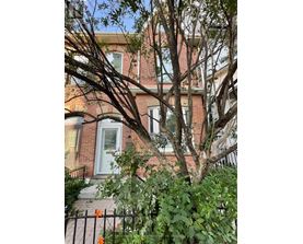 A tree in front of a red brick house.