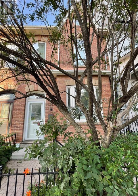 A tree in front of a red brick house.