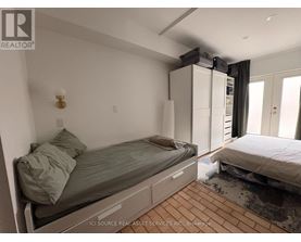 A bedroom with a bed, a nightstand, and a window with curtains.