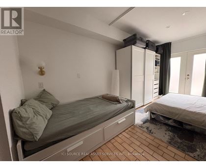A bedroom with a bed, a nightstand, and a window with curtains.