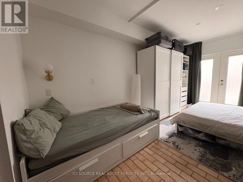 A bedroom with a bed, a nightstand, and a window with curtains.