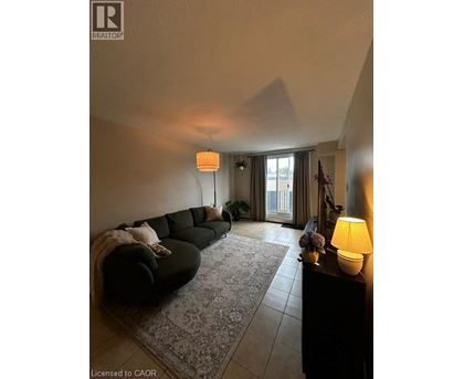 A living room with a black couch and a lamp on a table.
