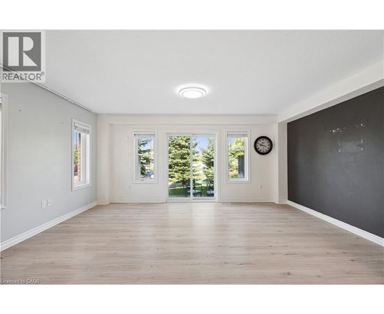A spacious room with wooden floors and a large window.