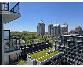 A view from a balcony of a building with a green lawn and several tall buildings in the background.