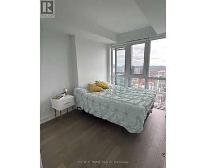 A bedroom with a bed, nightstand, and a window overlooking a cityscape.