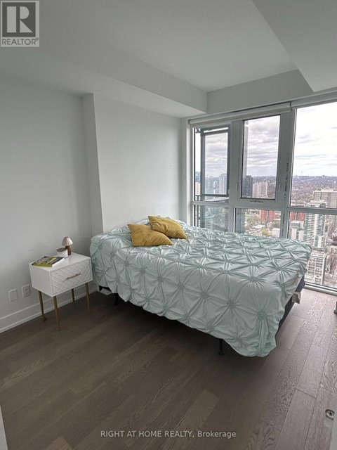 A bedroom with a bed, nightstand, and a window overlooking a cityscape.