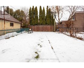 A snow-covered backyard with a fence and trees in the background.