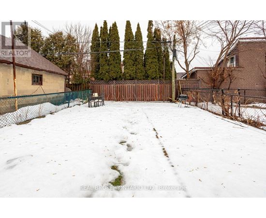 A snow-covered backyard with a fence and trees in the background.