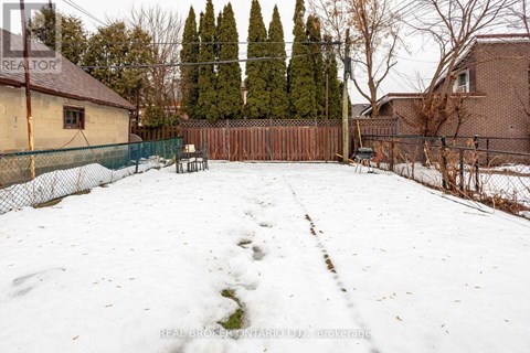 A snow-covered backyard with a fence and trees in the background.