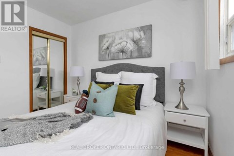A bedroom with a white bed and a grey headboard with a painting above it.