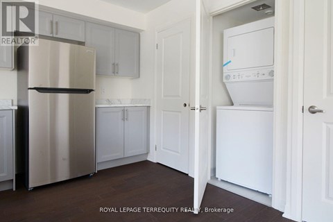 A kitchen with a refrigerator, cabinets, and a washer and dryer.