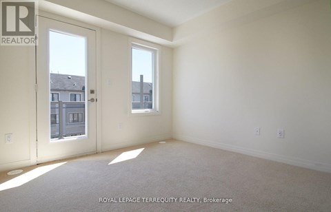 A white room with a carpet floor and two windows.