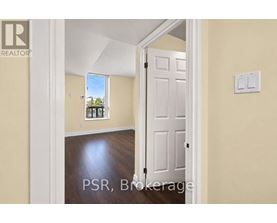 A room with a white door and a window showing a view of trees and a house.