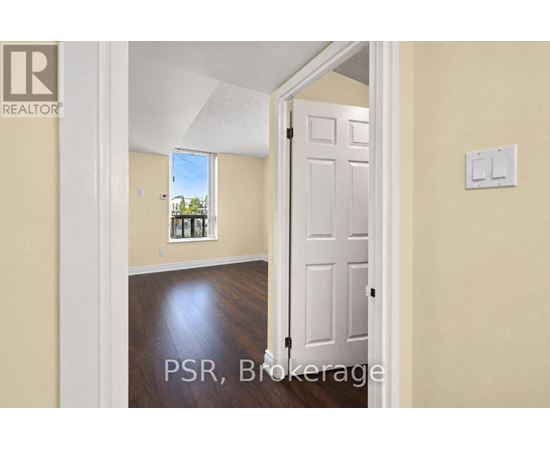 A room with a white door and a window showing a view of trees and a house.