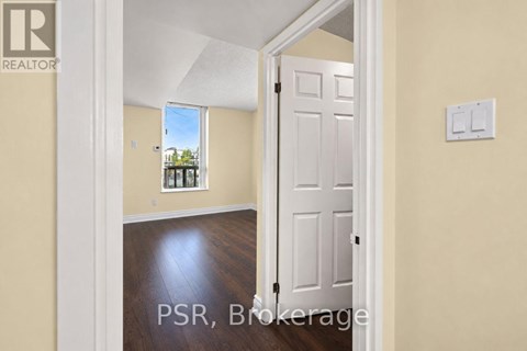 A room with a white door and a window showing a view of trees and a house.