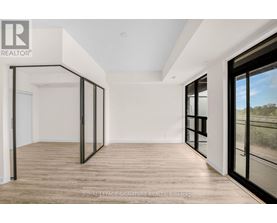 A spacious room with wooden flooring and large windows.