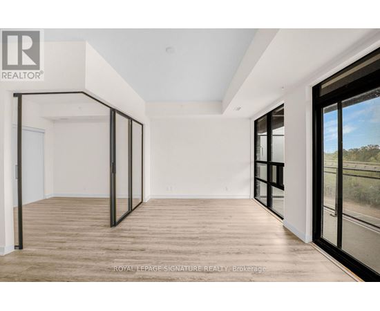 A spacious room with wooden flooring and large windows.
