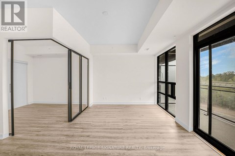 A spacious room with wooden flooring and large windows.