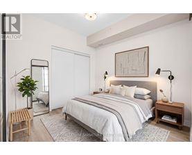 A bedroom with a large bed, a mirror, and a plant.