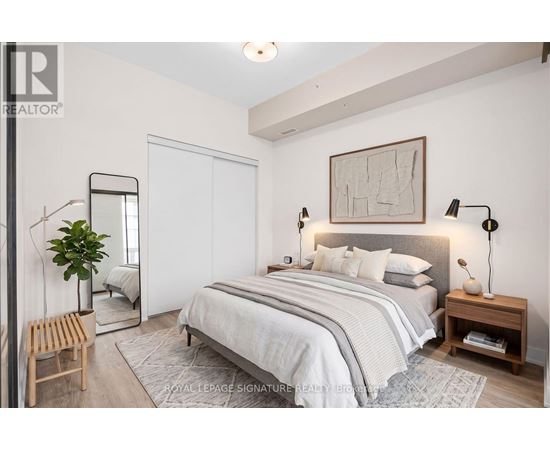 A bedroom with a large bed, a mirror, and a plant.