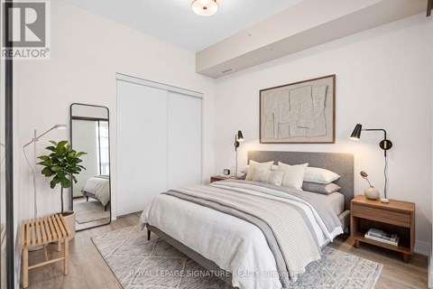 A bedroom with a large bed, a mirror, and a plant.
