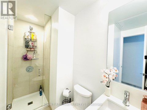 A white bathroom with a sink, toilet, and shower.