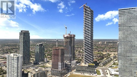 A cityscape with a clear blue sky and several high-rise buildings, one of which is under construction.