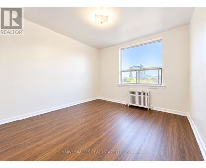 A room with wooden floors and a window showing an outdoor view.