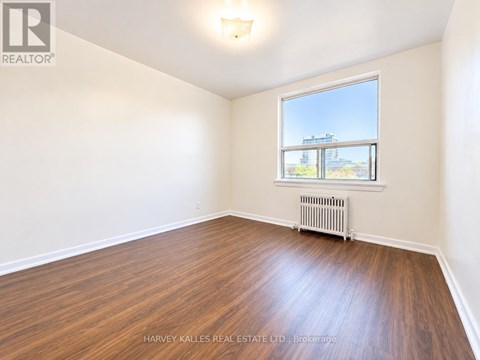 A room with wooden floors and a window showing an outdoor view.