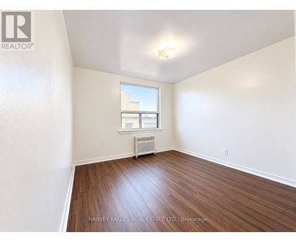 A room with wooden floors and a window with a view of a building outside.