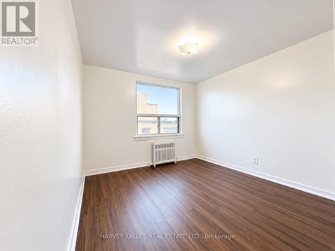 A room with wooden floors and a window with a view of a building outside.