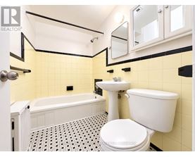 A white toilet sits in a bathroom with yellow tiles.