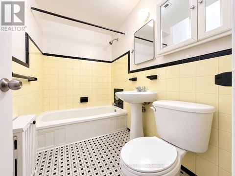 A white toilet sits in a bathroom with yellow tiles.