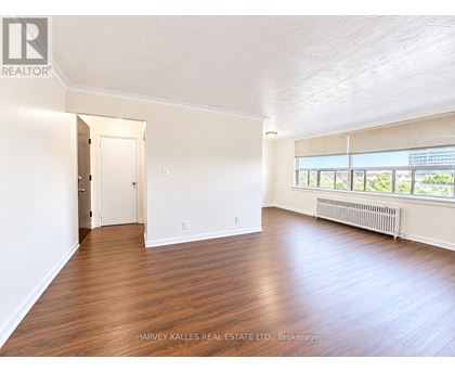 A spacious room with wooden floors and a large window.