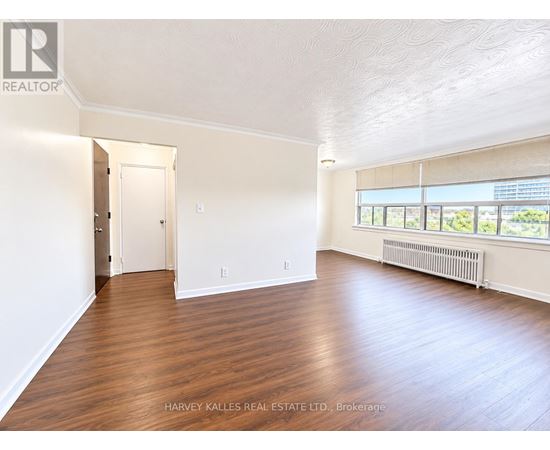 A spacious room with wooden floors and a large window.
