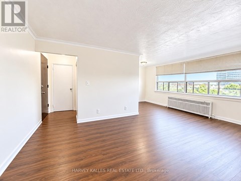 A spacious room with wooden floors and a large window.