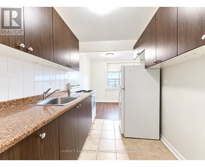 A kitchen with brown cabinets and a white refrigerator.