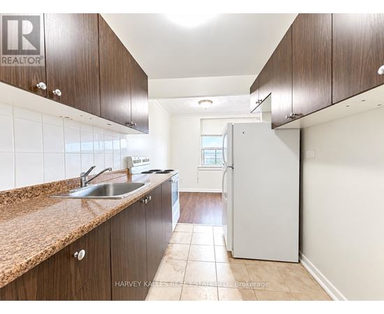 A kitchen with brown cabinets and a white refrigerator.