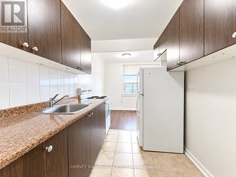 A kitchen with brown cabinets and a white refrigerator.
