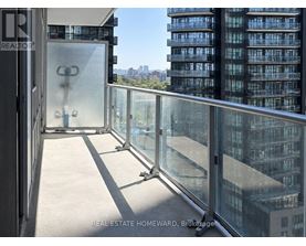A balcony with glass railings overlooks a cityscape.