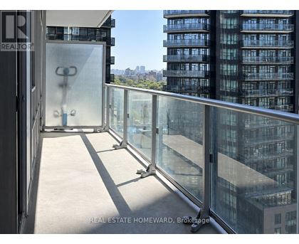 A balcony with glass railings overlooks a cityscape.