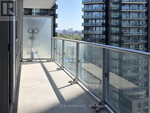 A balcony with glass railings overlooks a cityscape.
