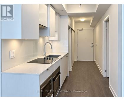 A modern kitchen with white cabinets and a dark countertop.
