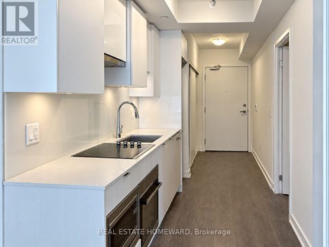 A modern kitchen with white cabinets and a dark countertop.