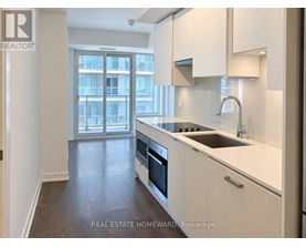A modern kitchen with white cabinets and a stainless steel sink.