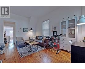 A living room with a brown couch and a red exercise bike.