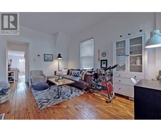 A living room with a brown couch and a red exercise bike.