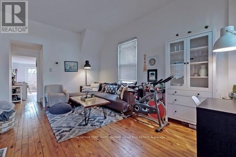 A living room with a brown couch and a red exercise bike.