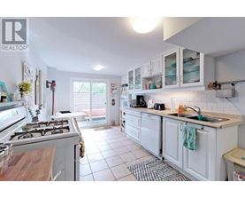 A white kitchen with a stove top oven and a sink.
